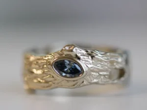 A tree-log textured ring with a blue memorial diamond in the middle