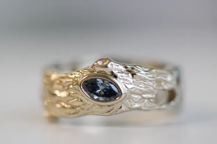 A ring with tree bark texture, with a blue memorial diamond in the middle.