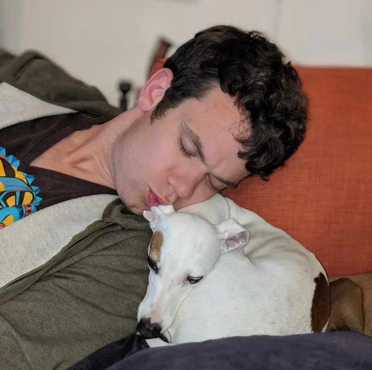 A man kissing a sleeping pup.