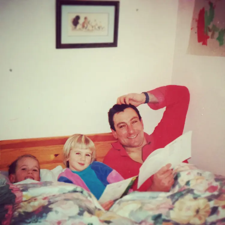 A dad, reading a bed time story to his son and daughter.