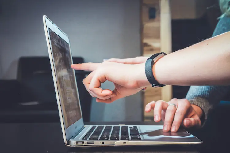 Two hands pointing at a computer screen.