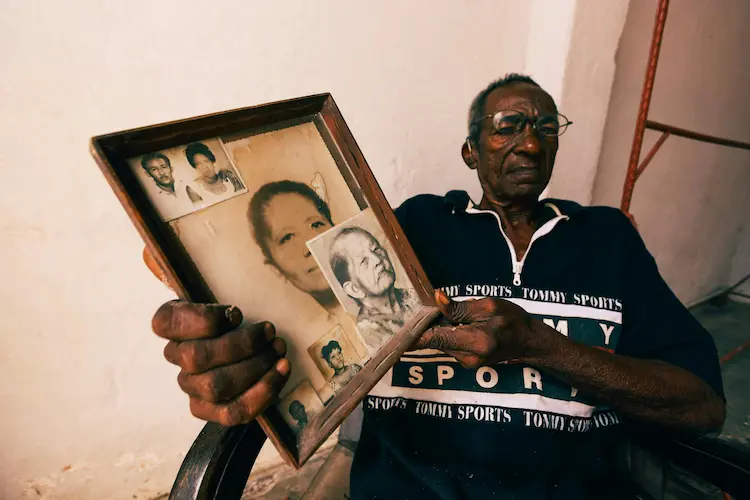 A man, holding up pictures of his relatives.