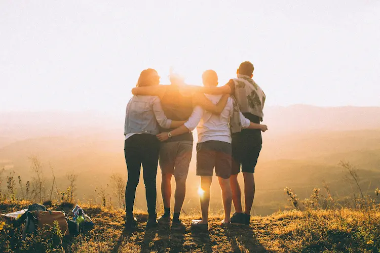 Four people hugging, watching the sunset.