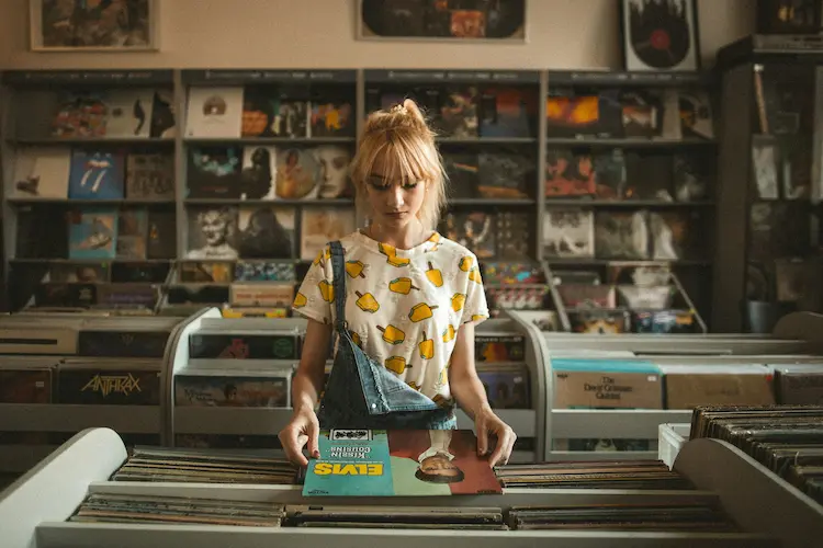 A woman, looking at vinyl's at a music store.