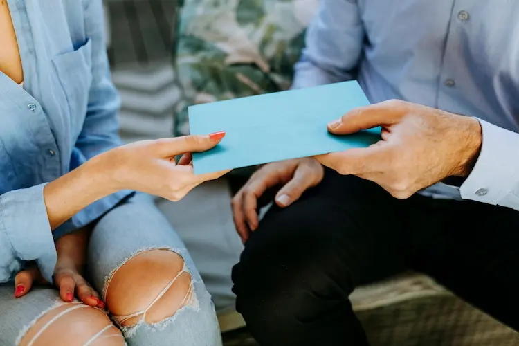 A person, handing a condolence letter to a friend.