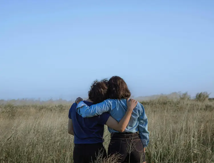 Two women hugging and looking at the landscape.