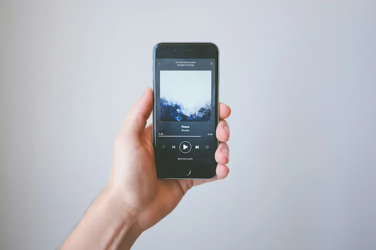 A man holding a phone, showing what song is playing.