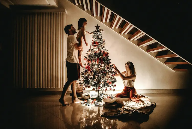 A family of three, setting up a christmas tree.