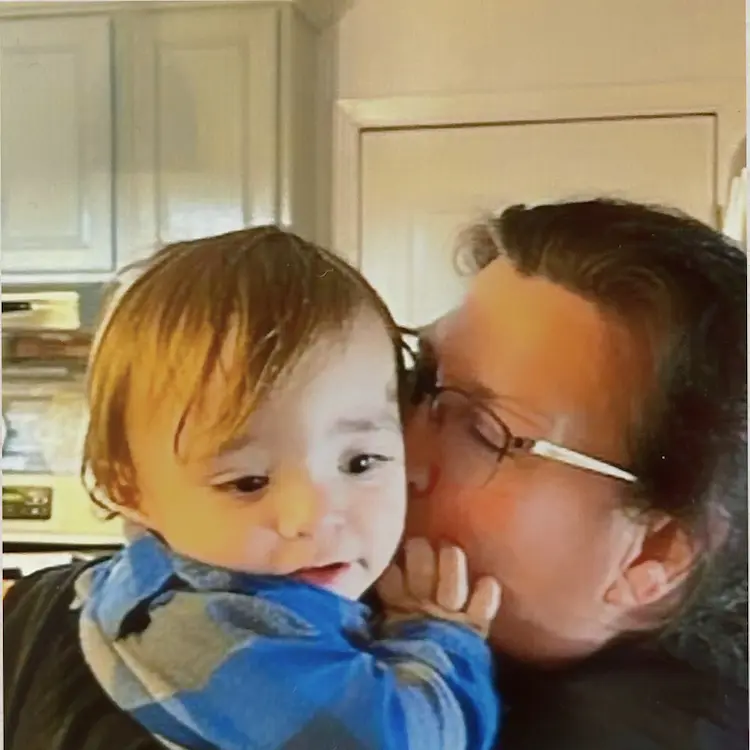 A grandma, holding and kissing her grandson.