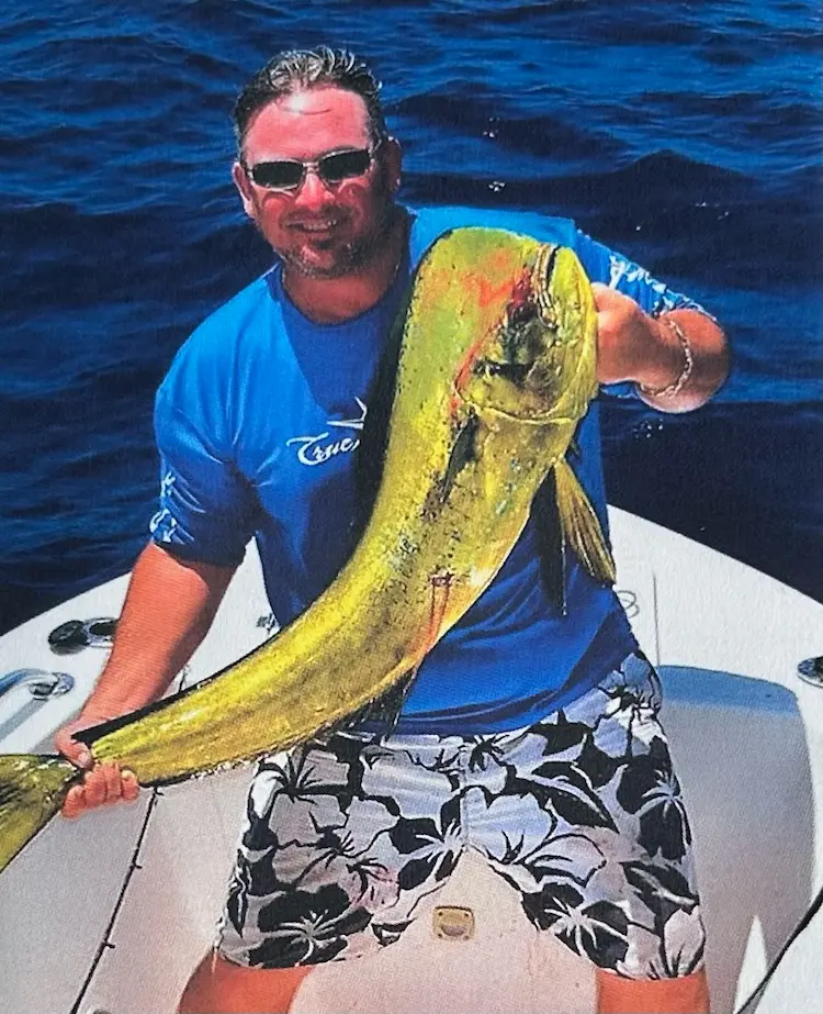 A man on a boat, holding a fish.