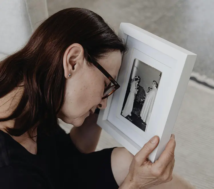 A woman crying and leaning over a picture of her loved ones.