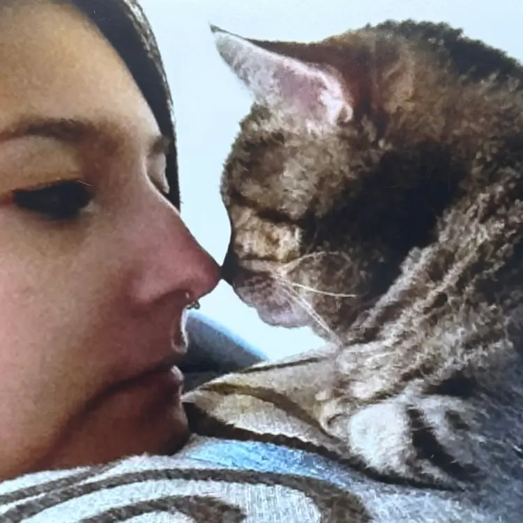 A woman touching noses with a tabby cat.