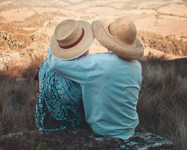 A couple hugging, sitting by mountains.